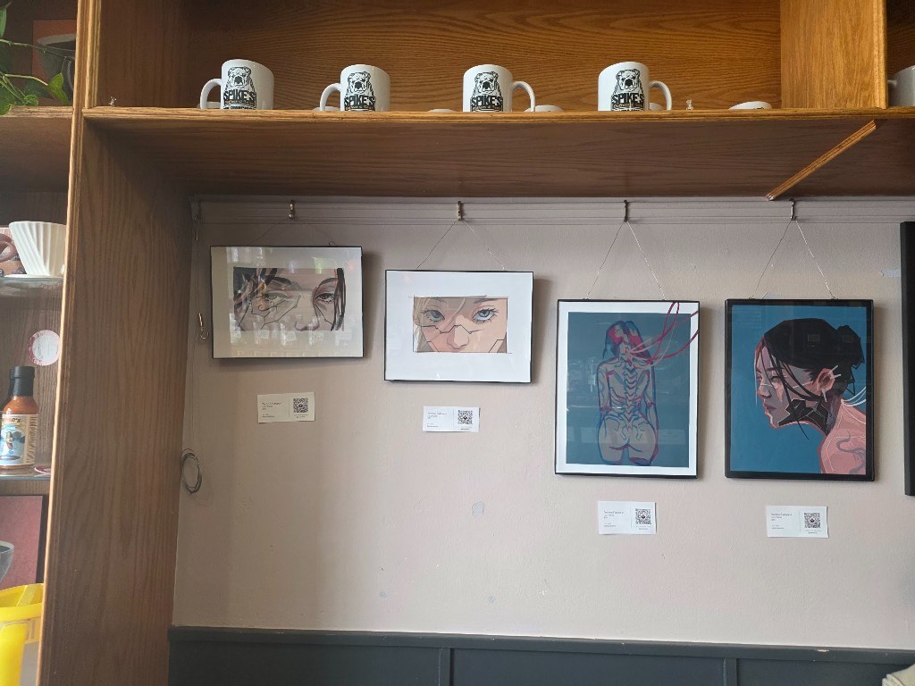 Framed drawings and prints hanging under a shelf of Spike's mugs