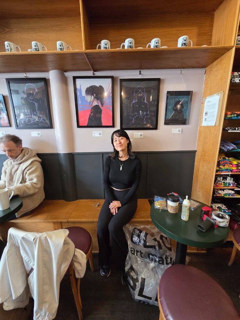 Lulu seated in front of the artwork at Spike's Coffee